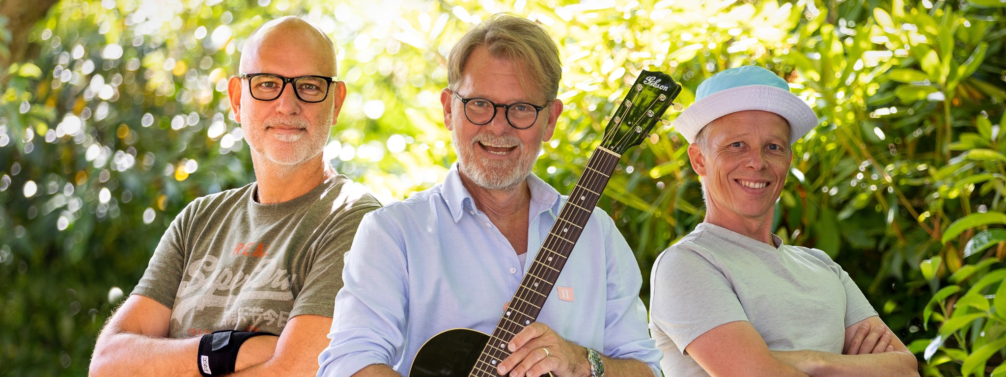Den Kummerlige Trio med guitar under grønne træer